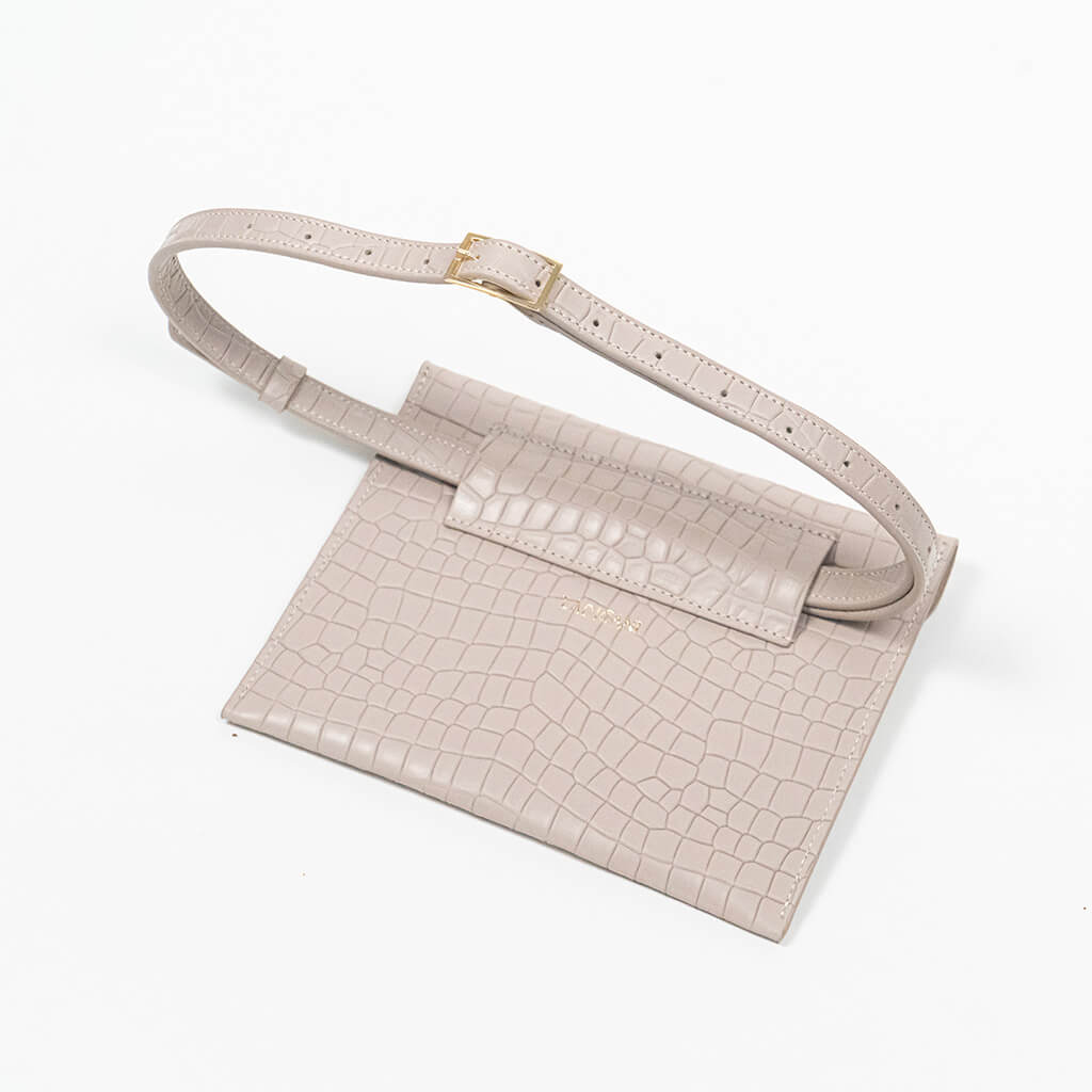 Back of a beige leather clutch bag with a raised strap on a white background, left side