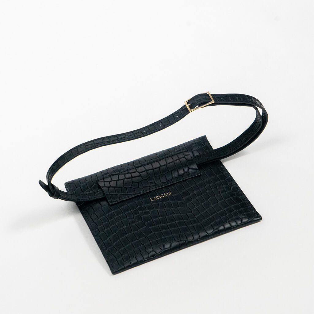 Back of a black leather clutch bag with a strap on a white background, right side