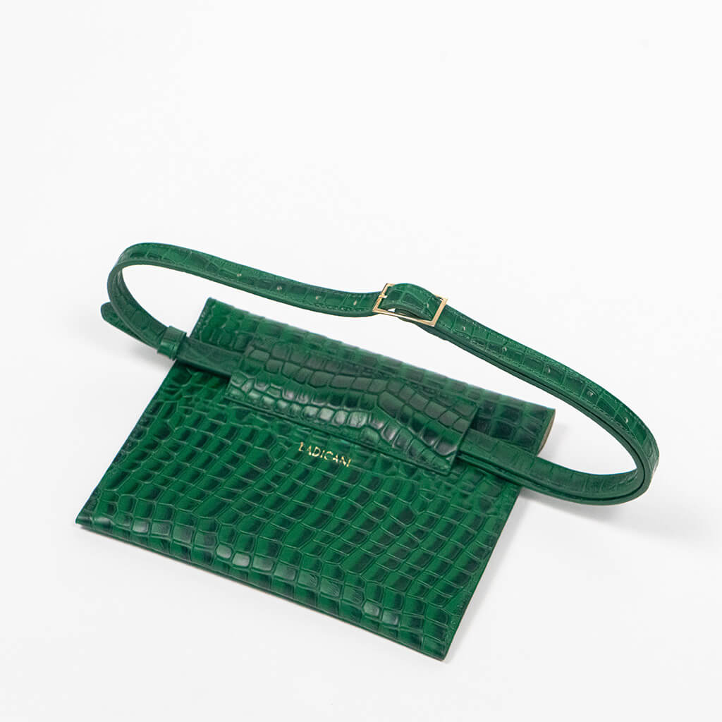 Back of a green leather clutch bag with a raised strap on a white background