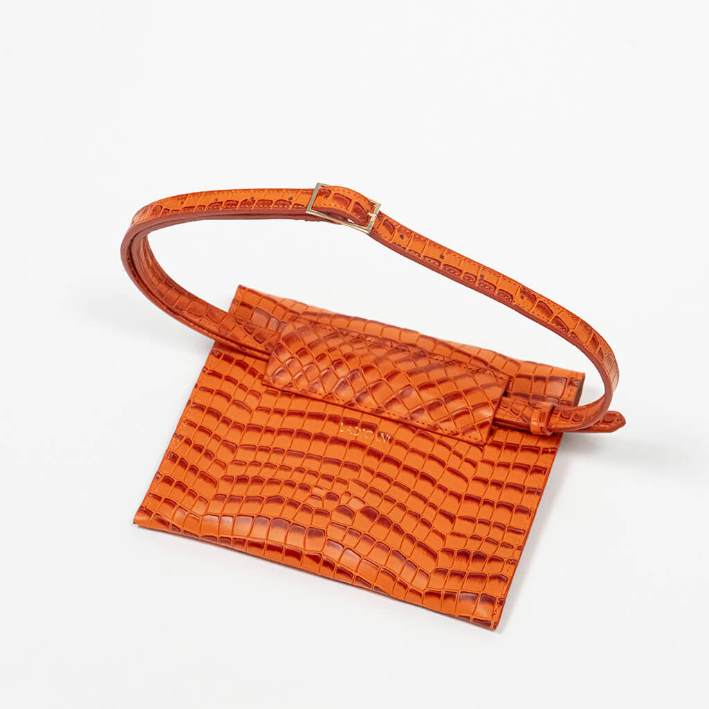 Back of an orange clutch bag with a raised strap on a white background