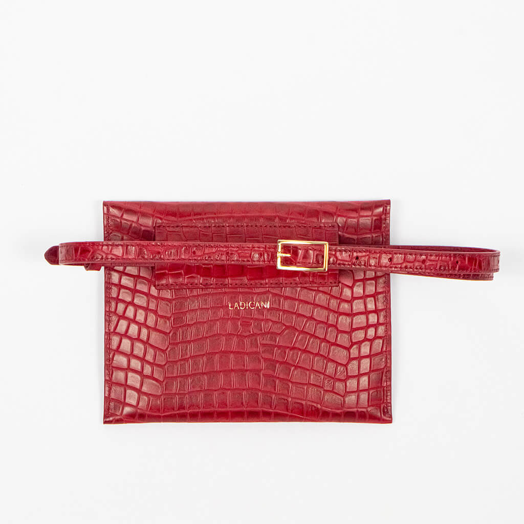 Back of a red leather clutch bag with a strap on a white background