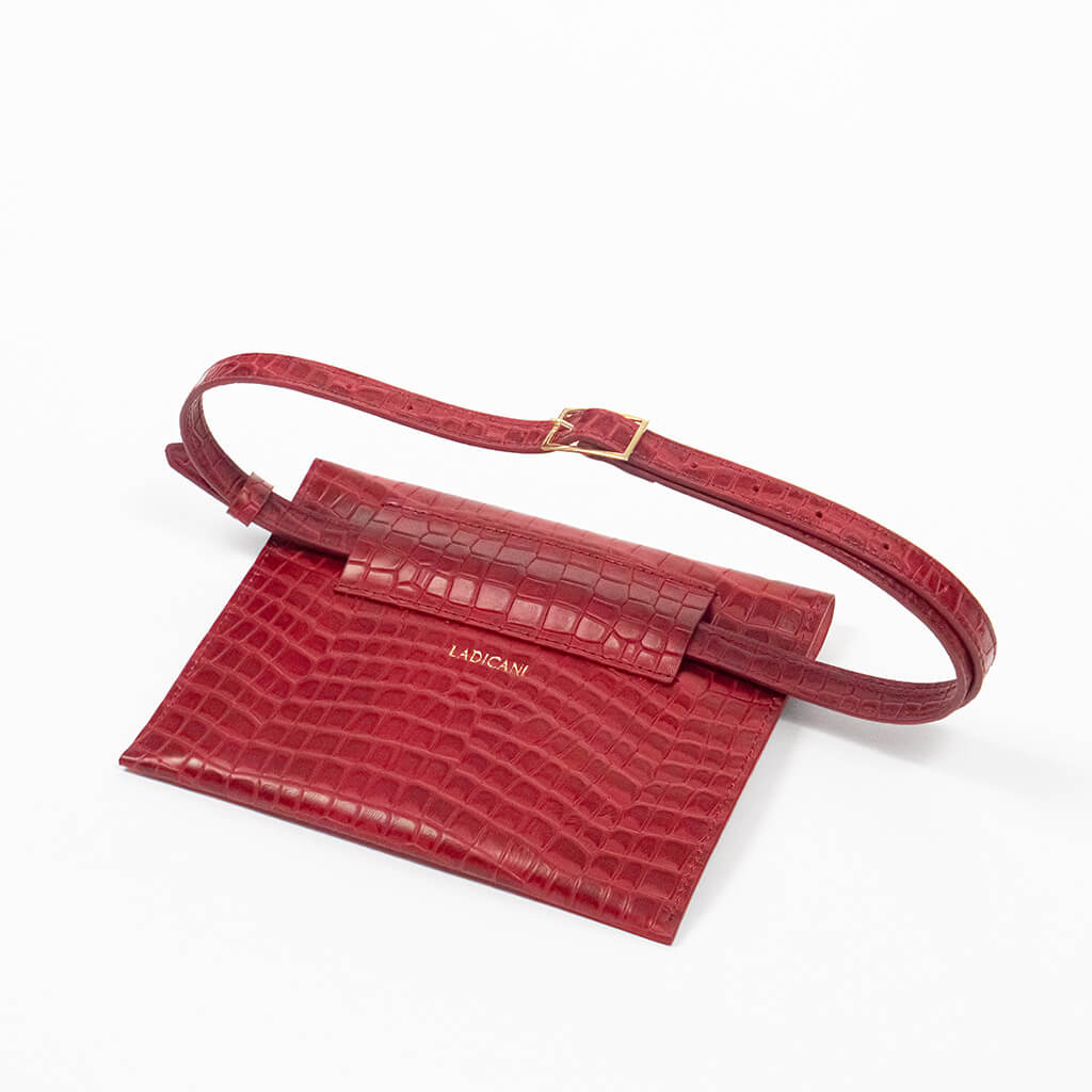 Back of a red leather clutch bag with a raised strap on a white background