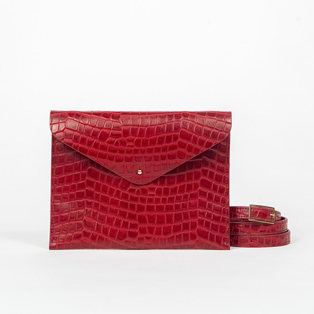 Red leather clutch bag with a strap on a white background