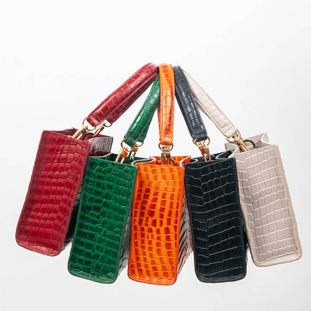 Set of five cassette bags in red, green, orange, black, and beige arranged next to each other on a white background