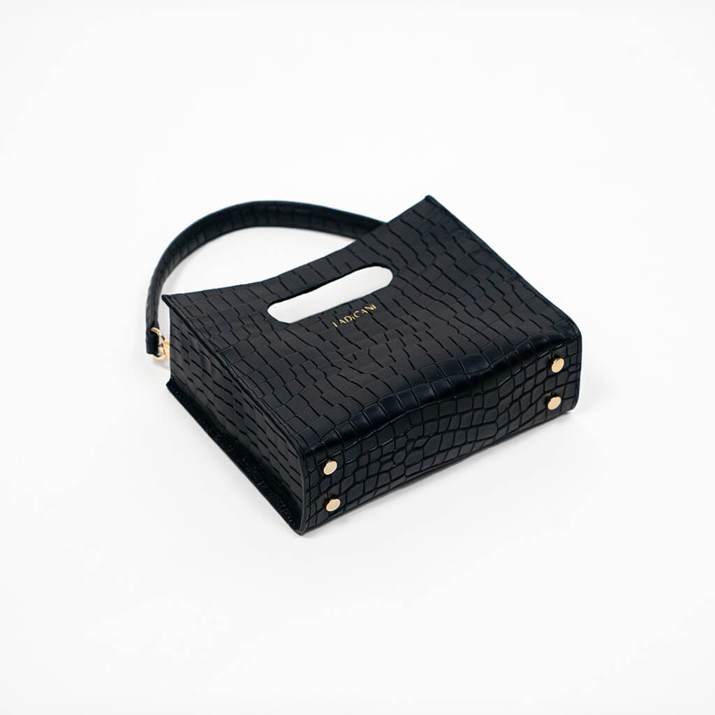 Black textured cassette bag with a visible brand logo and strap laying down on a white background