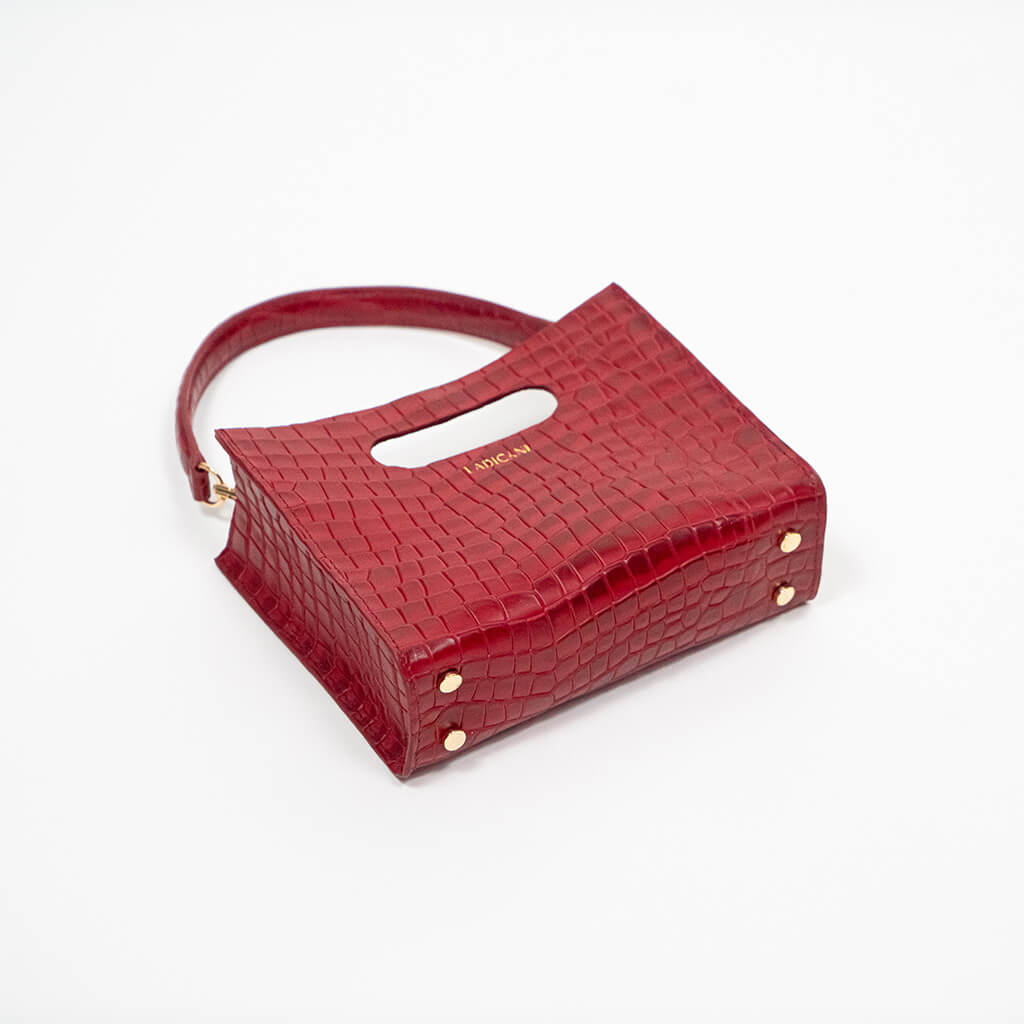 Beige textured cassette bag with a visible brand logo and strap laying down on a white background