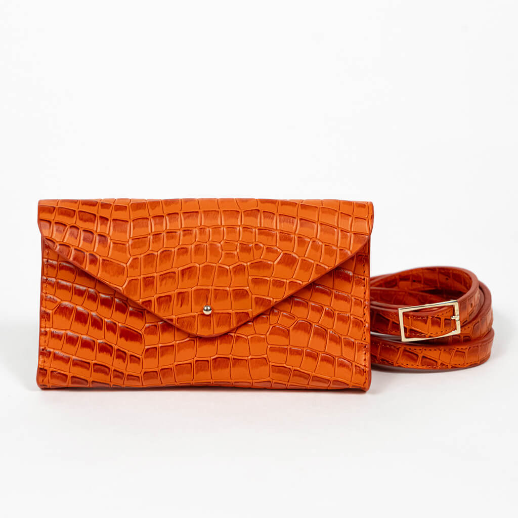 Orange mini clutch bag with matching belt on a white background