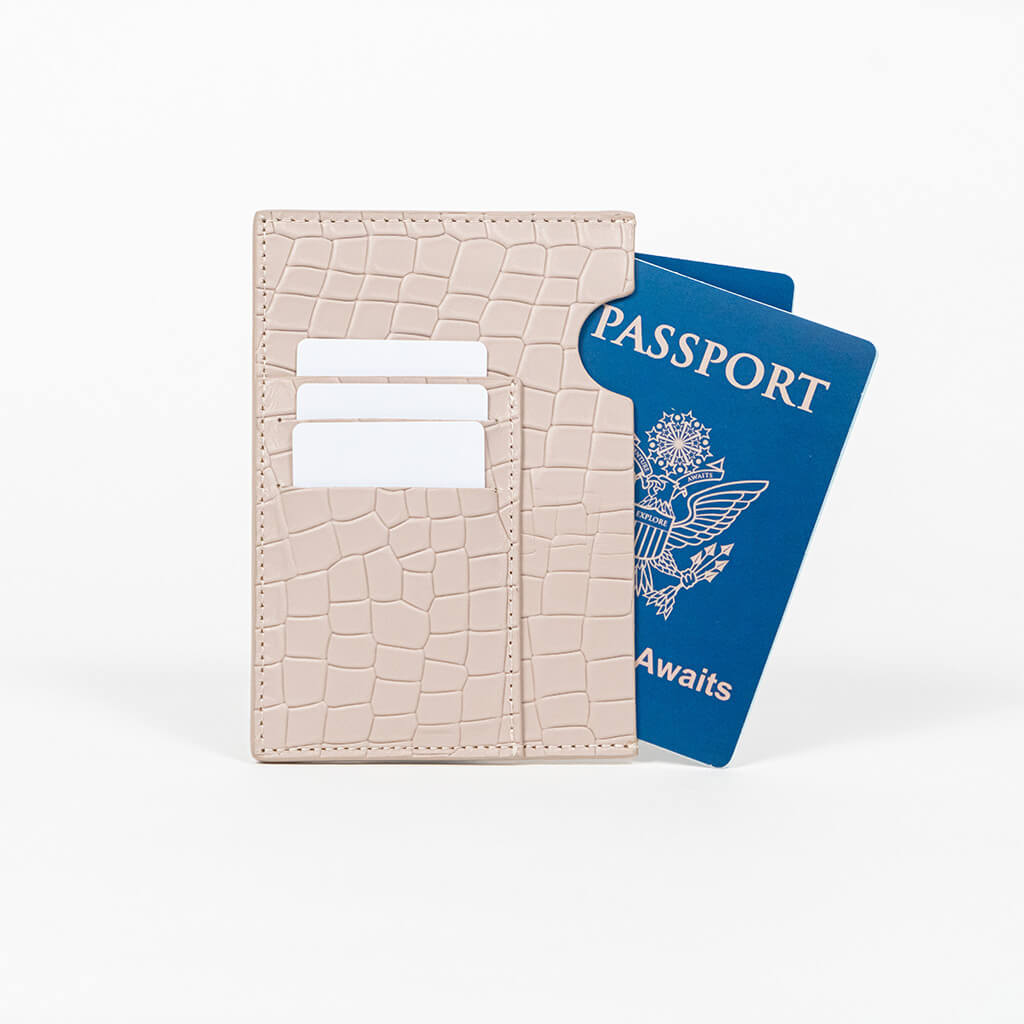 Beige leather passport holder with a blue passport on a white background