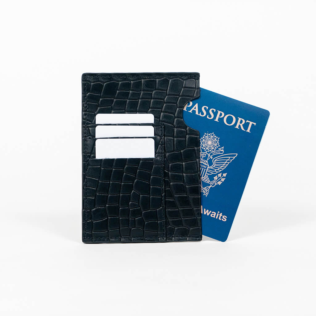 Black leather passport holder with a blue passport on a white background