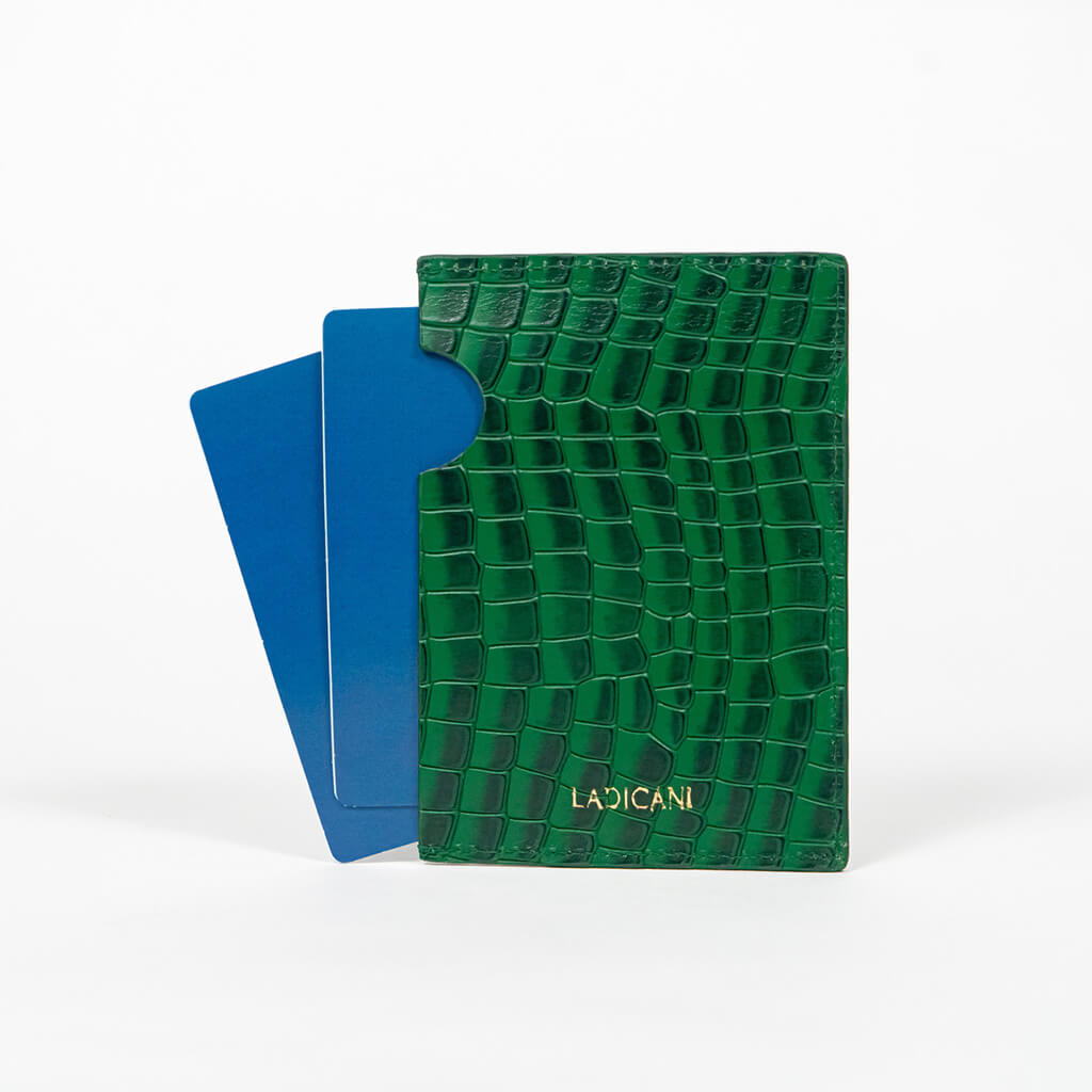 Back of a green leather passport holder with a blue passport on a white background