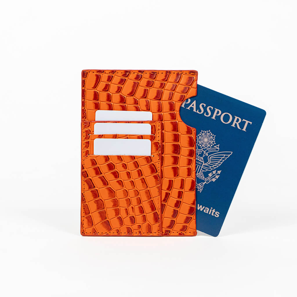 Orange leather passport holder with a blue passport on a white background