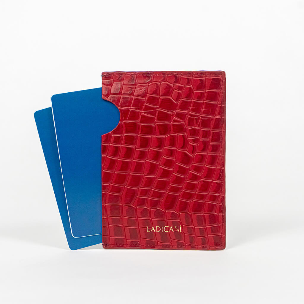 Back of a red leather passport holder with a blue passport on a white background