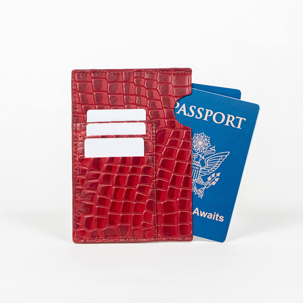 Red leather passport holder with a blue passport on a white background