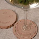 Smiley face leather coasters with a martini glass on a textured surface