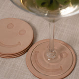 Smiley face leather coasters with a martini glass on a textured surface