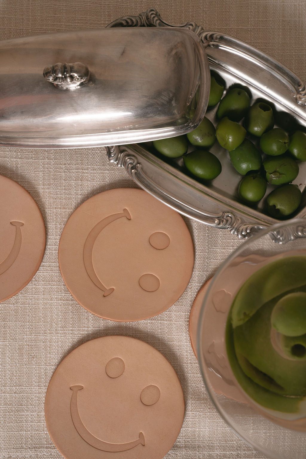Smiley face leather coasters with a martini glass on a textured surface
