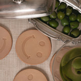 Smiley face leather coasters with a martini glass on a textured surface