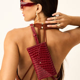 Woman wearing a red handbag with a unique design, standing against a plain background.