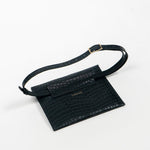 Back of a black leather clutch bag with a strap on a white background, right side