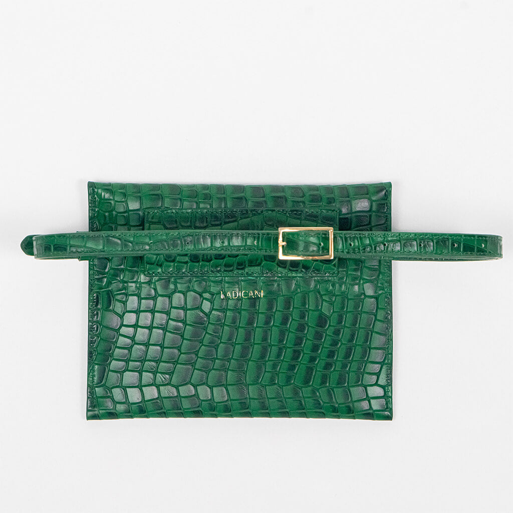 Back of a green leather clutch bag with a strap on a white background