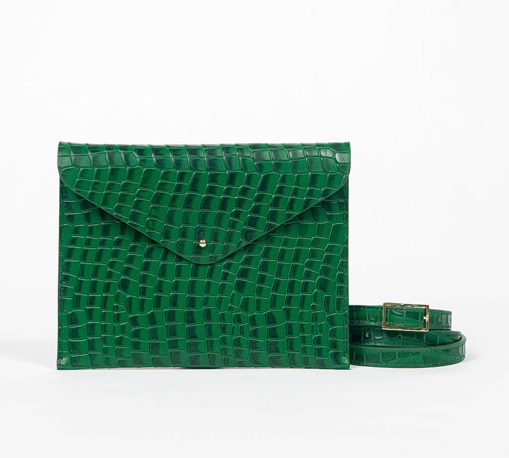 Green leather clutch bag with a strap on a white background