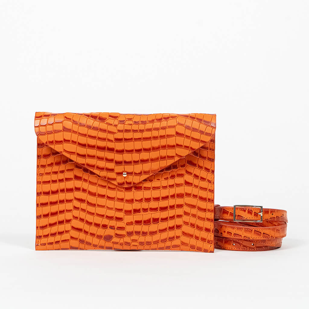 Orange clutch bag with a strap on a white background