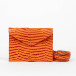 Orange clutch bag with a strap on a white background