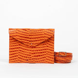 Orange clutch bag with a strap on a white background