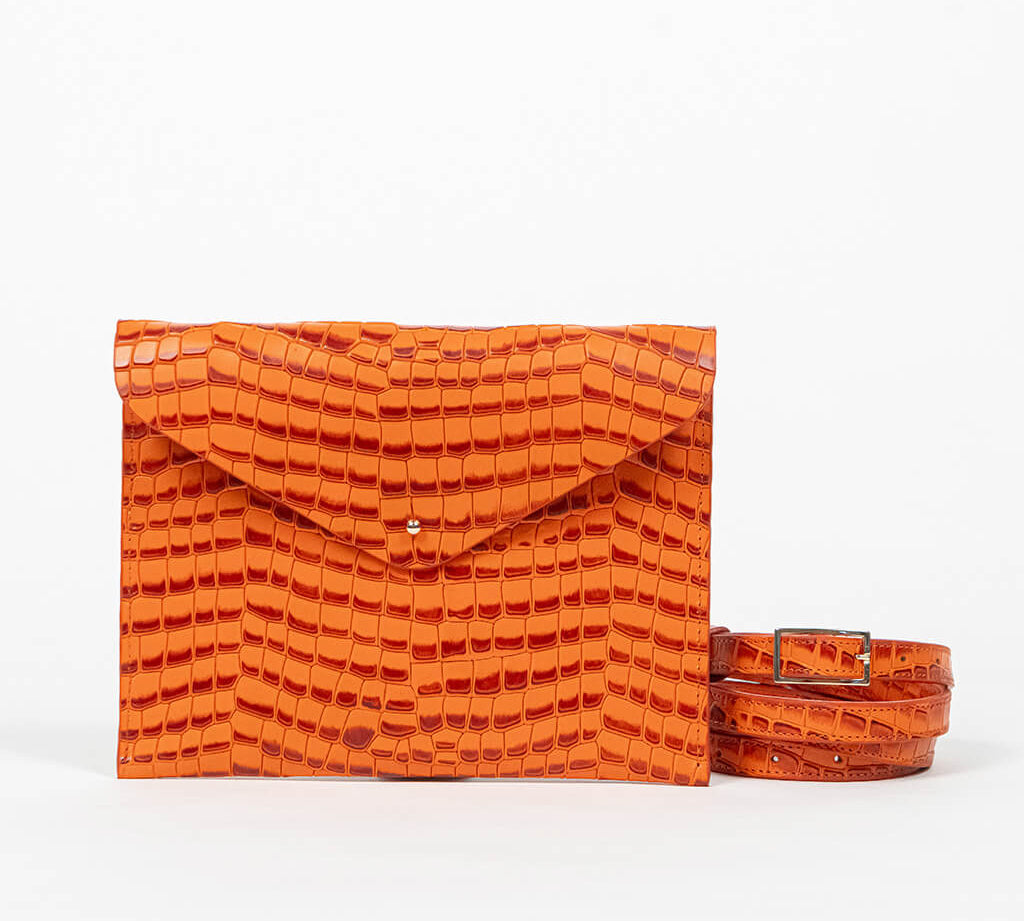 Orange clutch bag with a strap on a white background