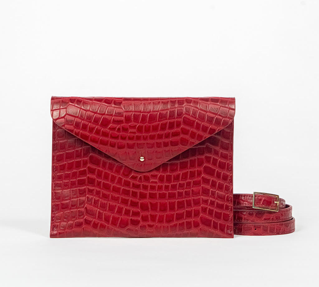 Red leather clutch bag with a strap on a white background