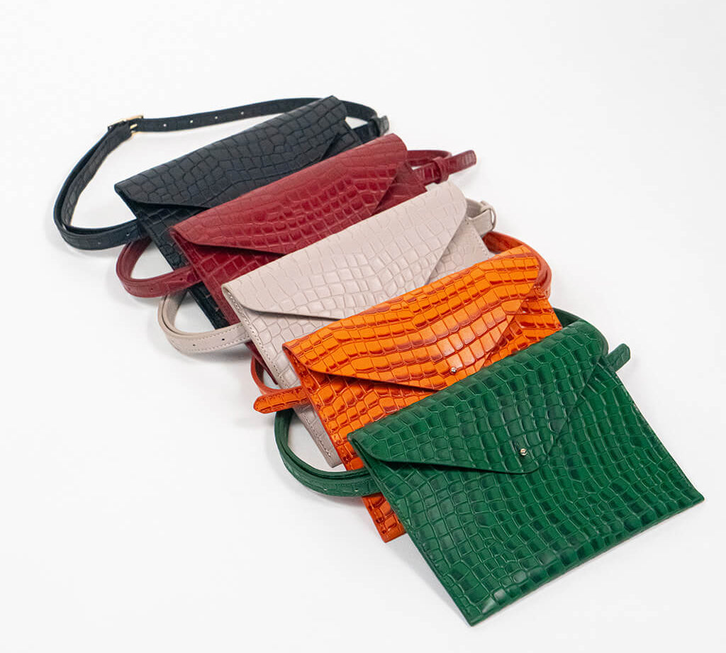 Five leather clutches in black, red, beige, orange, and green on a white background.