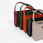 Set of five cassette bags in red, green, orange, black, and beige arranged in front of each other on a white background