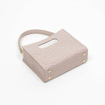Beige textured cassette bag with a visible brand logo and strap laying down on a white background