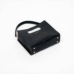 Black textured cassette bag with a visible brand logo and strap laying down on a white background