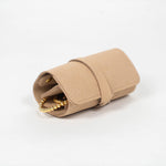 Closed beige leather jewelry roll with gold jewelry on a white background