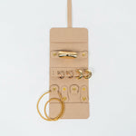Front of a beige leather jewelry roll with gold jewelry on a white background