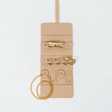 Front of a beige leather jewelry roll with gold jewelry on a white background