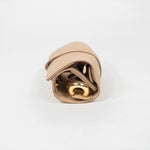 Closed beige leather jewelry roll with gold jewelry on a white background, side view