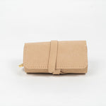 Closed beige leather jewelry roll with gold jewelry on a white background, front view