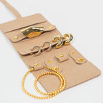Beige leather jewelry roll with gold jewelry on a white background