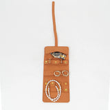 Open view of a brown leather jewelry roll with gold jewelry on a white background