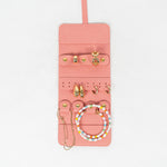 Front view of a pink leather jewelry roll with gold jewelry on a white background