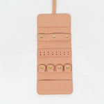 Open view of a light pink leather jewelry roll on a white background