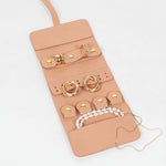 Light pink leather jewelry roll with gold jewelry on a white background