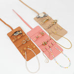 Three leather jewelry rolls in brown, pink, and beige with accessories on a white background
