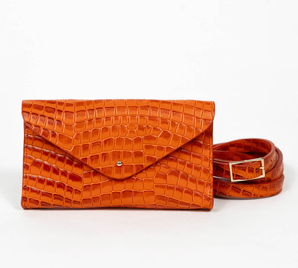 Orange mini clutch bag with matching belt on a white background