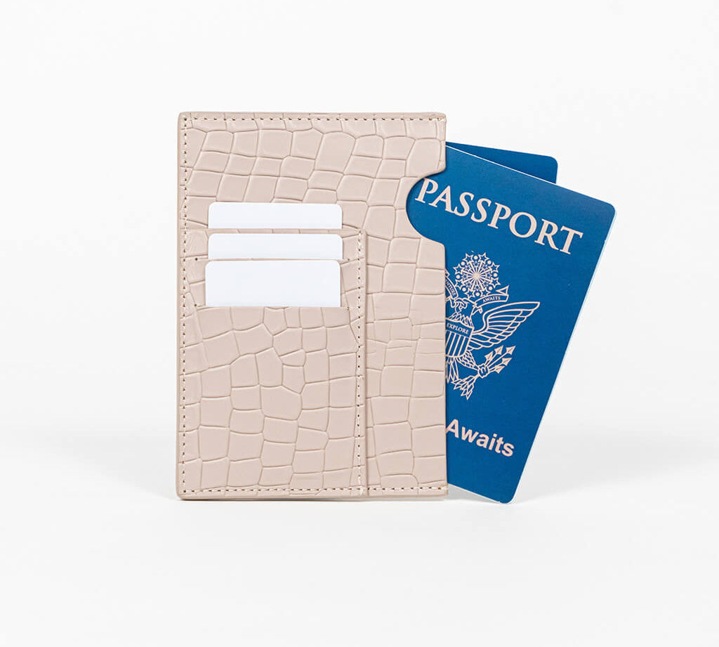Beige leather passport holder with a blue passport on a white background