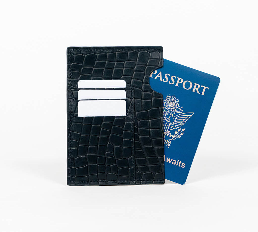 Black leather passport holder with a blue passport on a white background