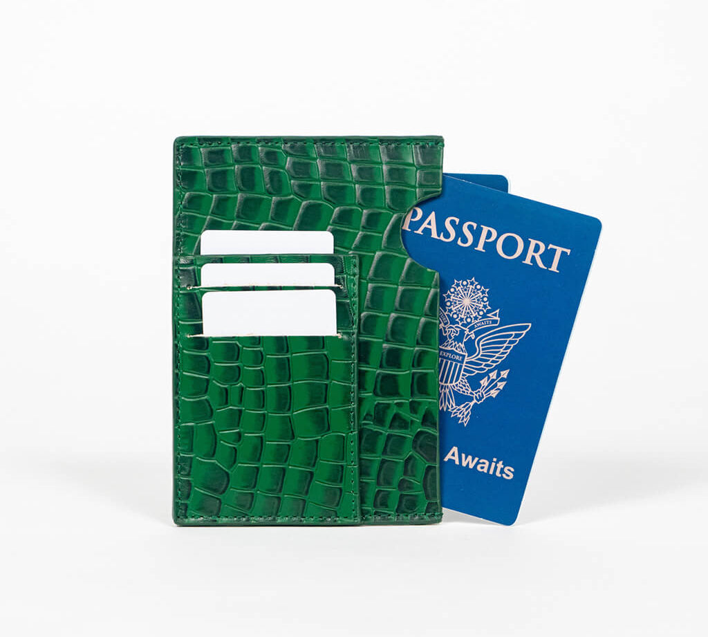 Green leather passport holder with a blue passport on a white background