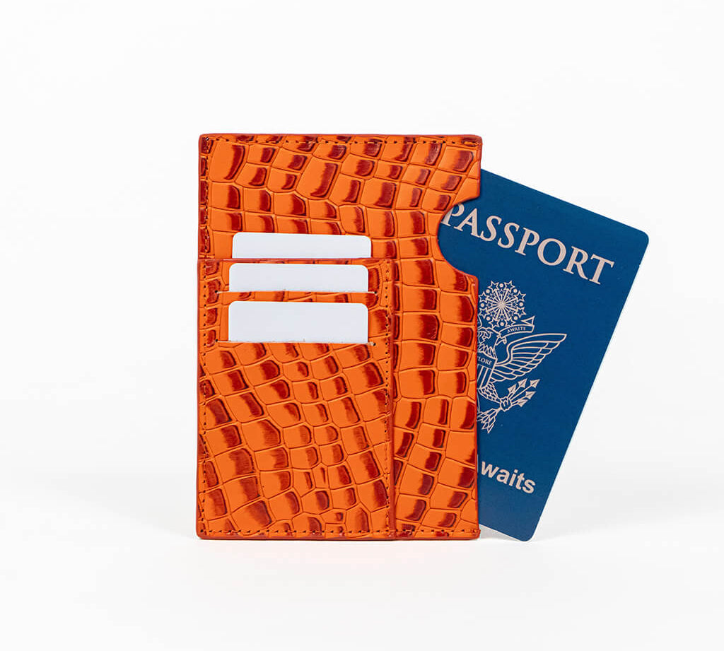 Orange leather passport holder with a blue passport on a white background